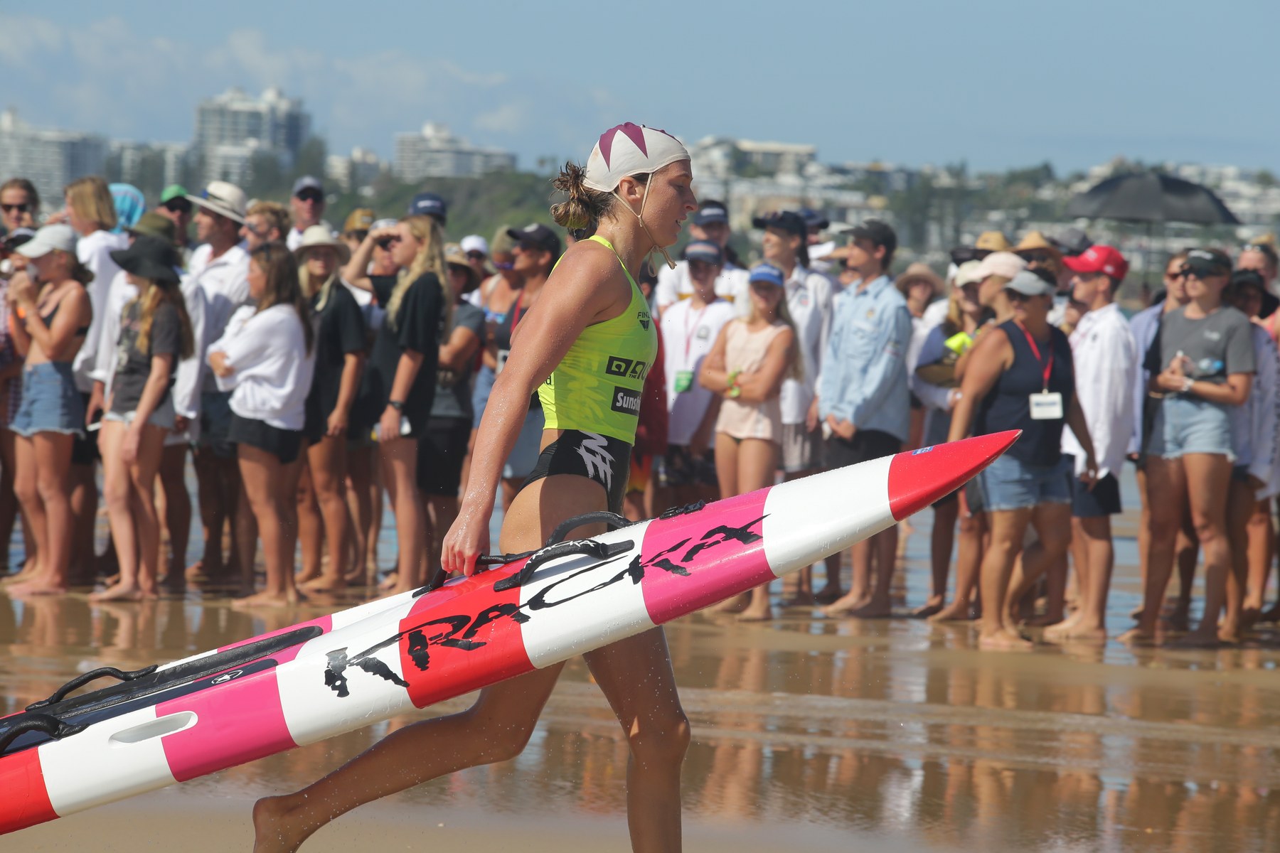 Jamie Perkins OAM Agency X Talent carrying her board in a surf lifesaving race